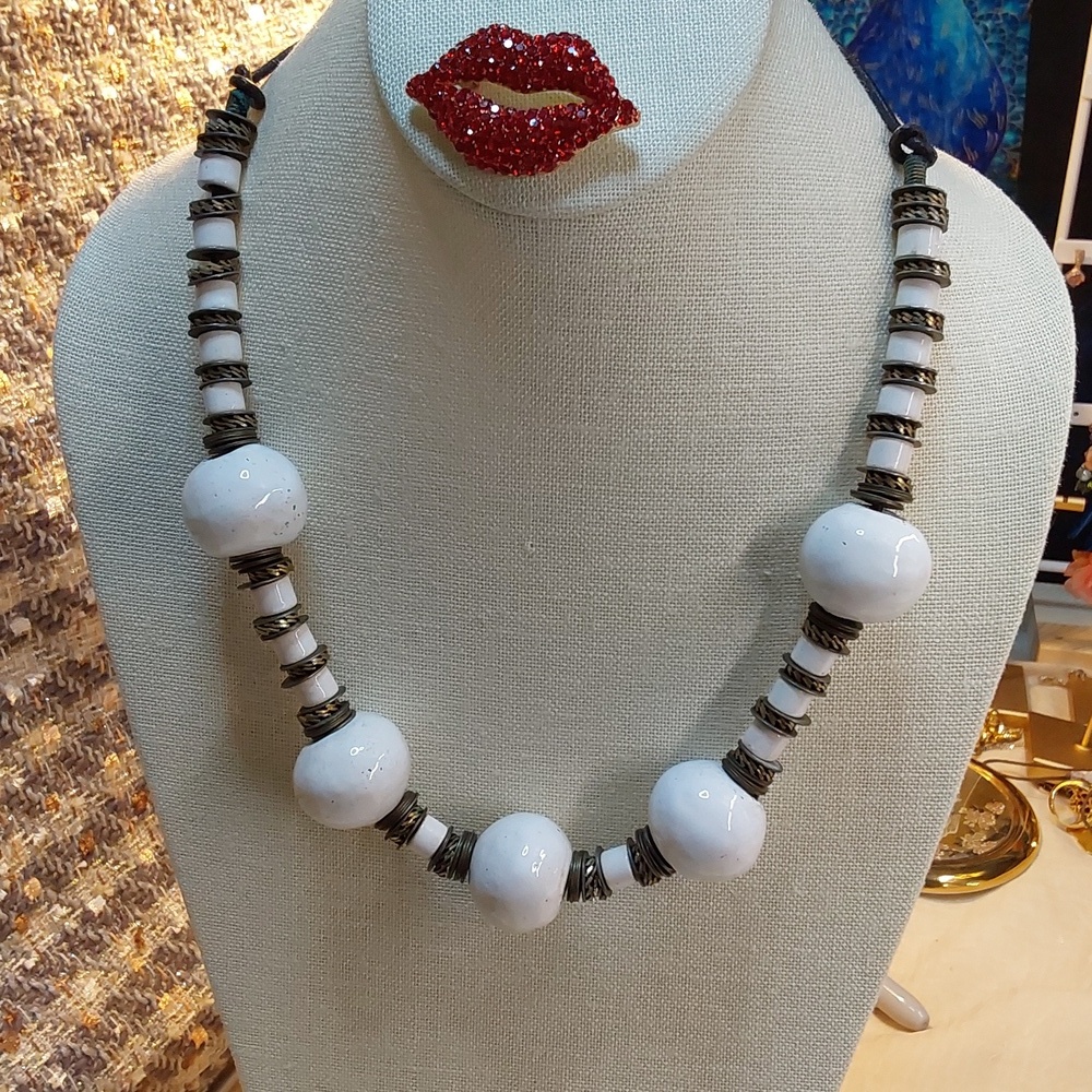 Ceramic and antique brass ending in leather and tied back to the clasp